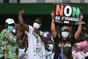 Yasmina Ouégnin, à droite, brandit une pancarte « Non au troisième mandat », lors d’un rassemblement, le 10 octobre 2020, à Abidjan. © SIA KAMBOU/AFP