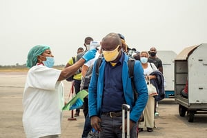 Un employé prend la température des passagers débarquant d’un vol d’Ethiopian Airlines à l’aéroport international N’Djili de Kinshasa le 15 août 2020. © Arsene Mpiana/AFP