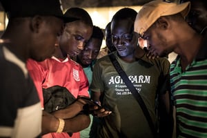 Des Guinéens regardent sur leurs smartphones la proclamation des résultats de la présidentielle du 18 octobre 2020 à Conakry, en Guinée. © JOHN WESSELS/AFP