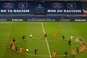 Les joueurs de foot et les arbitres, à genoux, en signe de protestation contre le racisme dans le foot. Le 9 décembre 2020 en amont du match PSG-Basaksehir au Parc des Princes à Paris. © XAVIER LAINE/AFP