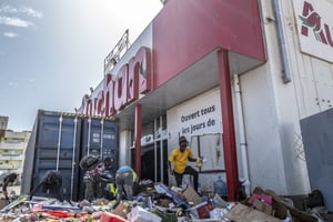 Des commerçants nettoient leur magasin dégradé lors des manifestations contre l’arrestation d’Ousmane Sonko à Dakar, en mars 2021. © CHERKAOUI SYLVAIN/AFP