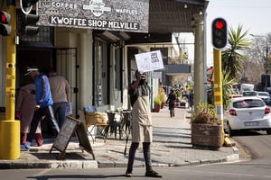 Un homme tient un panneau sur lequel est écrit « Les emplois sauvent des vies » à l’extérieur d’un restaurant à Johannesburg, en Afrique du Sud, le 22 juillet 2020. © Yeshiel/Xinhua/REA
