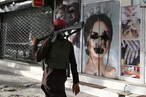 Taliban passant devant un salon de beauté dégradé, à Kaboul, le 18 août 2021. © Wakil KohsarAR/AFP