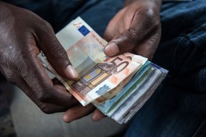 Un homme échange des euros contre des francs CFA ouest-africains, à Abidjan, en Côte d’Ivoire, en septembre 2015. © Jose Cendon/Bloomberg/Getty