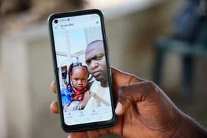 Wuri Bailo Keita tient un téléphone portable montrant une photo de lui et de sa défunte fille, Fatoumata, qui serait décédée d’une insuffisance rénale aiguë, à Banjul le 10 octobre 2022. © MILAN BERCKMANS/AFP