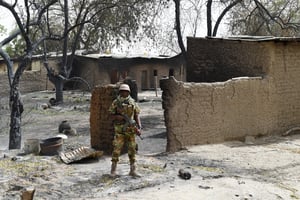 Un soldat monte la garde devant une maison incendiée à Malam Fatori reprise aux militants islamistes de Boko Haram, le 3 avril 2015. © PHILIPPE DESMAZES / AFP