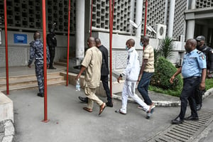Des officiers de police escortent les quatre accusés présents au tribunal pour l’ouverture du procès de l’attentat de Grand-Bassam, à Abidjan le 30 novembre 2022. © Sia Kambou/AFP