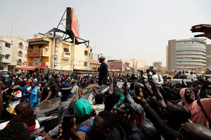Le chef de l’opposition sénégalaise, Ousmane Sonko, sur le toit d’une voiture après son audience au tribunal à Dakar, le 16 février 2023. © ZOHRA BENSEMRA/REUTERS