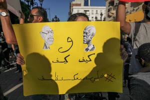 Caricature de Kaïs Saïed regardant Rached Ghannouchi, sur laquelle on peut lire en arabe : « Ils sont pareils, gardez votre doigt propre » lors d’une manifestation de l’opposition tunisienne à Tunis, le 22 juillet 2022. © Chedly Ben Ibrahim / NurPhoto / NurPhoto via AFP