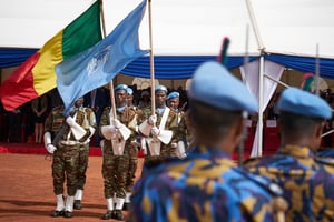 Des soldats tiennent les drapeaux de l’ONU et du Mali lors de la cérémonie de la Journée des Casques bleus à la base opérationnelle de la Minusma (Mission multidimensionnelle intégrée des Nations unies pour la stabilisation au Mali) à Bamako, le 29 mai 2018. © Michele CATTANI/AFP