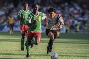 L’attaquant camerounais Roger Milla file au but après avoir subtilisé la balle au gardien colombien Jose Higuita, à Naples, le 23 juin 1990, en match de poule de la Coupe du monde. © AFP)