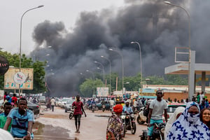 De la fumée s’élève après que des partisans du coup d’État ont mis le feu au siège du Parti pour la démocratie et le socialisme au Niger, du président Mohamed Bazoum, à Niamey, au Niger, le 27 juillet 2023. © Balima Boureima / Anadolu Agency via AFP