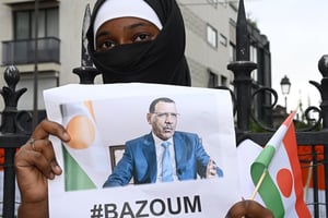 Une jeune femme manifeste en soutien au président Mohamed Bazoum, à Paris le 5 août 2023. © A woman holds the image of ousted Niger President Mohamed Bazoum, 63, who has been held by coup plotters with his family in his official Niamey residence since July 26, during a protest outside the Niger Embassy, in Paris on August 5, 2023. – A West African delegation failed to secure the return to power of Niger’s elected government on August 4, 2023, despite proposals to resolve the crisis as the junta curtailed military cooperation with former colonial power France. Pressure on the leaders of a coup in Niger mounted on August 5, 2023, on the eve of a west African bloc’s deadline for the military to relinquish control or face possible armed intervention. (Photo by STEFANO RELLANDINI / AFP)