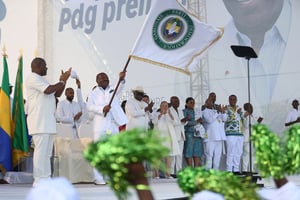 Le président gabonais Ali Bongo Ondimba brandit le drapeau du Parti démocratique gabonais au stade Nzeng-Ayong, à Libreville, le 10 juillet 2023, un jour après avoir annoncé qu’il briguerait un troisième mandat. © Steeve JORDAN/AFP