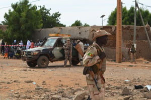 Des soldats maliens se tiennent à côté d’un bâtiment détruit en novembre 2018 à Gao, après un attentat suicide à la voiture piégée, faisant trois victimes parmi les civils.  © AFP