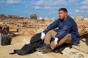 Un volontaire assis sur les décombres d’un bâtiment dans une zone endommagée à Derna, le 14 septembre 2023. © Abdullah DOMA / AFP