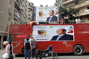 Des soutiens du président Abdel Fattah Al-Sissi déploient, sur un bus du Caire, une banderole à son effigie, en amont de l’élection présidentielle qui se déroulera du 10 au 12 décembre. © Khaled DESOUKI/AFP