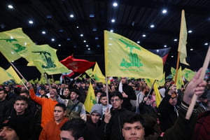Dans la banlieue sud de Beyrouth le 3 janvier 2024, des partisans brandissent des drapeaux du Hezbollah lors des commémorations de l’anniversaire de l’assassinat du haut commandant iranien Qassem Soleimani. © ANWAR AMRO / AFP