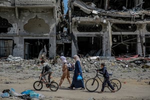 Des Palestiniens marchent à côté de bâtiments détruits dans le nord de la bande de Gaza, le 21 mars 2024. © AFP