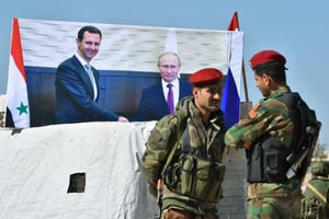 Portraits de Bachar el-Assad et de Vladimir Poutine derrière des soldats syriens, à Abu al-Duhur, dans le nord de la Syrie, en 2018. © George Ourfalian / AFP
