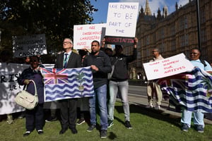 Des membres de la communauté chagossienne rassemblés avec des banderoles et des pancartes devant le Parlement britannique pour protester contre la décision du gouvernement de céder les îles Chagos à l’île Maurice, le 7 octobre 2024. © Adrian DENNIS / AFP