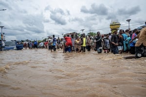 Des habitants pataugent dans des eaux troubles à la suite de fortes pluies, dans le quartier de Ndjili à Kinshasa, le 6 avril 2025. © Hardy BOPE/AFP