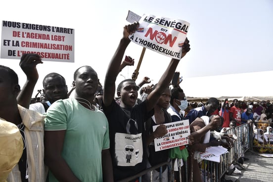 Des manifestants brandissent des pancartes alors qu’ils participent à Dakar, le 20 février 2022, à une manifestation réclamant un durcissement des mesures répressives contre l’homosexualité. © SEYLLOU / AFP