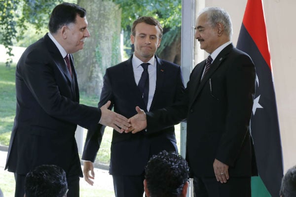 Le président du conseil présidentiel libyen Fayez al-Sarraj (g.) et le commandant de l’armée nationale libyenne Khalifa Haftar, se serrent la main sous le regard d’Emmanuel Macron, président français, à l'issue de la rencontre de ce mardi 25 juillet près de Paris. &copy; Michel Euler/AP/SIPA