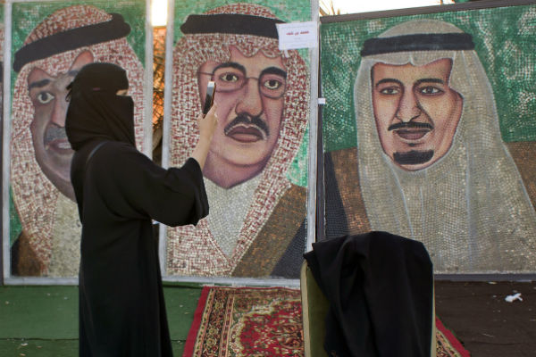 une femme prend des photos de portraits du roi d'Arabie saoudite et de son fils, prince héritier, à Jeddah, le 8 février 2017. &copy; Amr Nabil/AP/SIPA