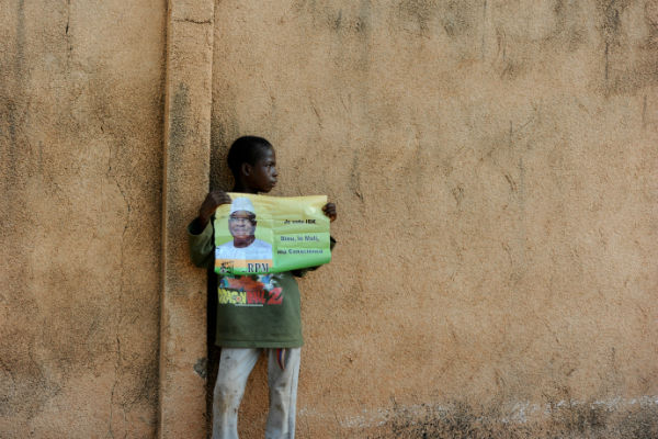 Un enfant tient une affiche de campagne d'Ibrahim Boubacar Keïta, lors de la campagne présidentielle de 2013, à Bamako. &copy; Émilie Régnier pour Jeune Afrique