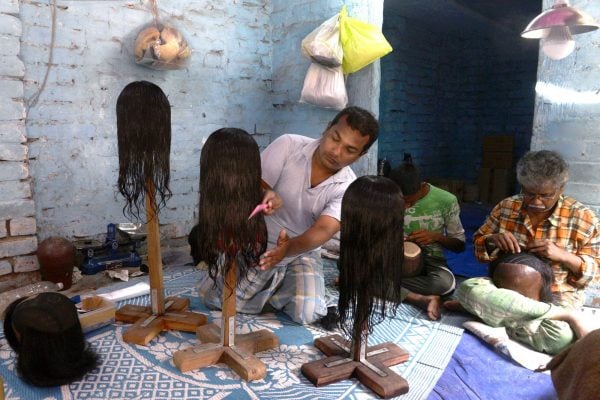 Un ouvrier indien peignant une perruque de cheveux naturels dans un atelier. &copy; Paul saikat/SIPA