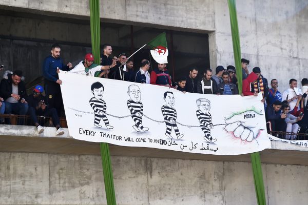 Des manifestants tenant une banderole où sont représentés en détenus Saïd Bouteflika, Abdelmadjid Sidi Saïd, Ali Haddad et Ahmed Ouyahia, le 15 mars, à Alger. &copy; RYAD KRAMDI/AFP
